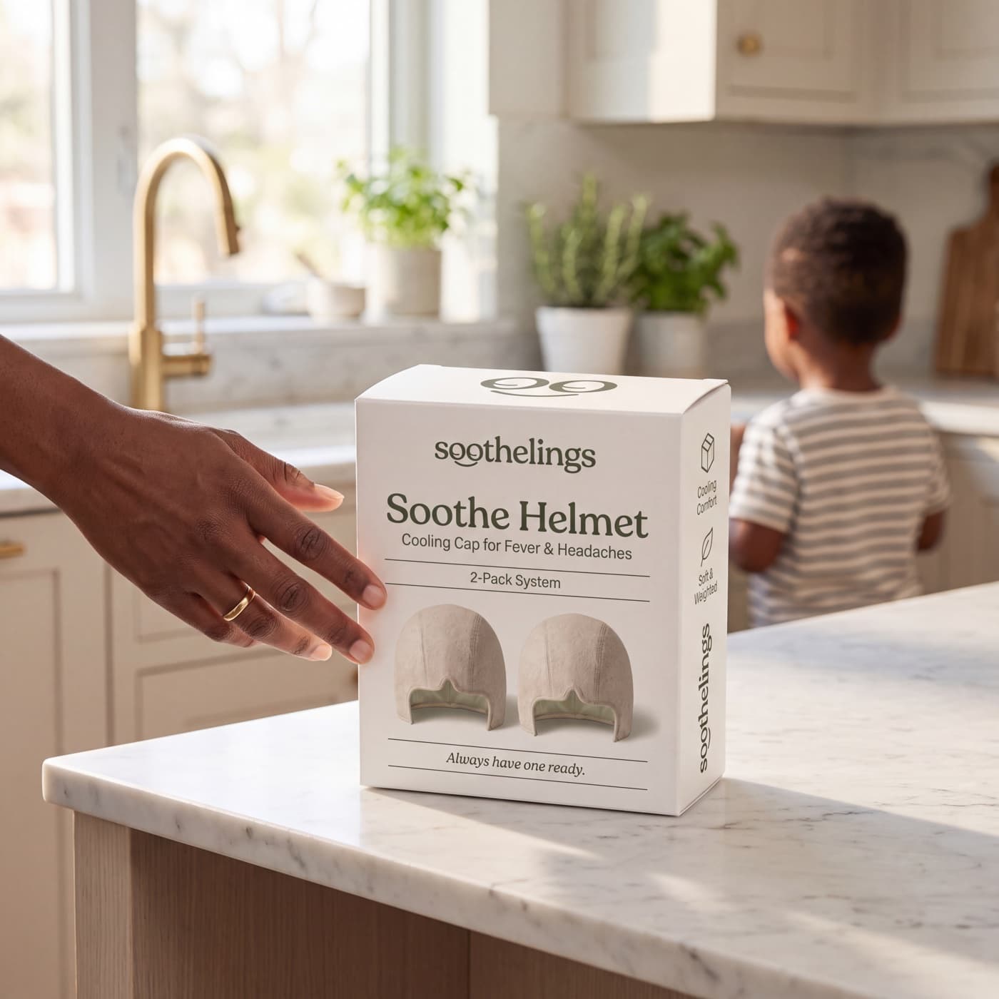 A parent reaching for the soothelings Soothe Helmet 2-pack carton on a kitchen island, their child standing turned away in the background.